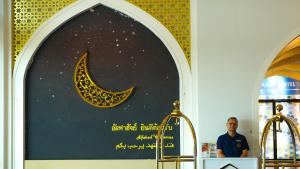合艾Alfahad Hotel的一名男子站在一块画着新月的标志牌前