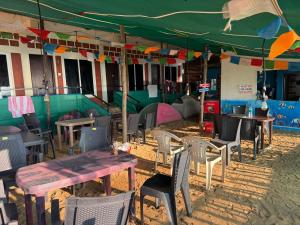 Un grupo de mesas y sillas debajo de una carpa. en Aisiri comforts beach stay and cafe, en Gokarn