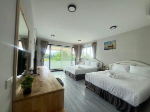 une chambre d'hôtel avec deux lits et une télévision dans l'établissement Lucky 9 Airport Hotel Phuket, à Nai Yang Beach