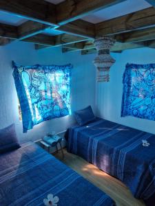 two beds in a room with blue lights at Cabaña Pakarati in Hanga Roa
