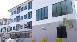 a white building with a car parked in front of it at Fun Hotel in Ban Thai Wat Khot