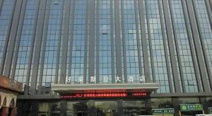 a large building with a sign in front of it at Quanzhou Jinjiang Hollyston Hotel in Jinjiang