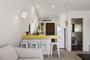a kitchen and living room with a counter and stools at Okawa Bay Lakeside - Lake Rotoiti A-Frame in Mourea