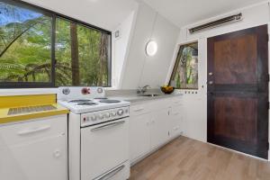 a white kitchen with a stove and a window at Okawa Bay Lakeside - Lake Rotoiti A-Frame in Mourea +23 photos