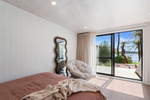 a bedroom with a bed and a large window at Okawa Bay Lakeside - Lake Rotoiti A-Frame in Mourea