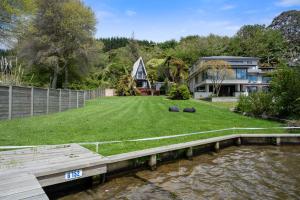 a house with a yard next to a body of water at Okawa Bay Lakeside - Lake Rotoiti A-Frame in Mourea