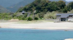a house sitting on a beach next to the water at Hotel Nagoku in Tosashimizu