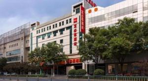 a large white building with a red sign on it at Ibis Xinzhou Qiyi RD in Xinzhou Zhan
