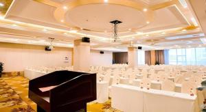 ein großer Raum mit weißen Stühlen und einem Flügel in der Unterkunft Vienna International Hangzhou Future Science City in Hangzhou