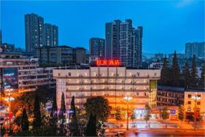 a building with a neon sign on it in a city at Home Inn Neo Leshan Central Food Street in Leshan