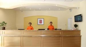 two men in orange shirts standing at a cash counter at Home Inn-Qingdao Chongqing Zhong Road Licang Walking Street in Laoshan