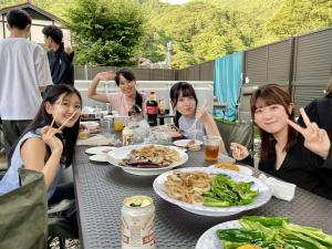 a group of people sitting at a table eating food at 貸切宿さうなす in Nasushiobara