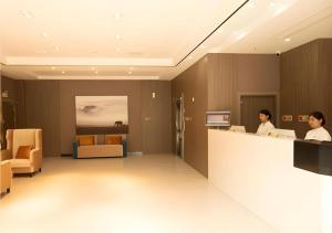 zwei Frauen sitzen an einem Tresen in einer Krankenhauslobby in der Unterkunft Jtour Inn Wuxi Meiyuan Kaiyuan Temple Metro in Wuxi