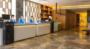 eine Gruppe von Menschen, die an einem Tresen in einer Lobby stehen in der Unterkunft Echarm Hotel Guilin Zhongshan Zhong Road Liangjiang Sihu in Guilin