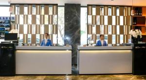 zwei Personen sitzen an einem Schreibtisch in einem Büro in der Unterkunft Echarm Hotel Guilin Zhongshan Zhong Road Liangjiang Sihu in Guilin