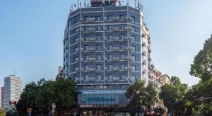 ein hohes blaues Gebäude mit Bäumen davor in der Unterkunft City Comfort Inn Wuhan Dongwu Avenue Light Rail Station in Wuhan