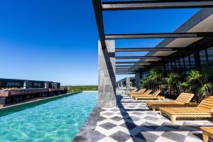 a row of lounge chairs on a building with a swimming pool at Tulum Escape - Private Hot Tub, Steps to Free Beach in Tulum