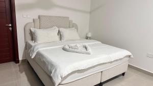 Una cama blanca con dos animales de peluche. en Kayan 1 bhk 10 mins from everywhere in Muscat, en Maţār as Sīb ad Duwalī