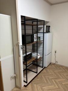a room with a kitchen with a microwave and a refrigerator at 貸切戸建 ベッドルーム4 シングルベッド9 釧路駅近く in Kushiro