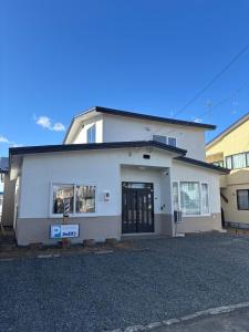 a white building with a sign in front of it at 貸切戸建 ベッドルーム4 シングルベッド9 釧路駅近く in Kushiro
