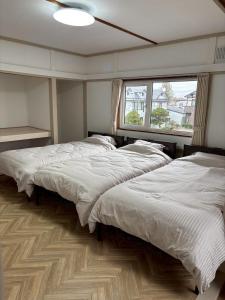 a bedroom with three beds and a window at 貸切戸建 ベッドルーム4 シングルベッド9 釧路駅近く in Kushiro