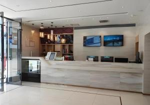 a lobby with a counter with two monitors on the wall at City Comfort Inn Guilin Yangshuo Shili Hualang Qianguqing in Yangshuo