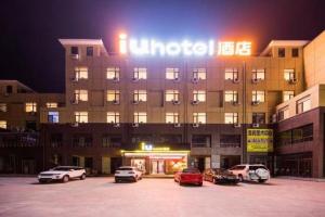 T'ao-hua TaoにあるIU Hotels· Xincheng Haibing University Storeの駐車場に車が駐車されている大きな建物