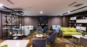 ein Wohnzimmer mit einem gelben Sofa und Stühlen und Tischen in der Unterkunft James Joyce Coffetel Jilin Railway Station Fortune Plaza in Jilin