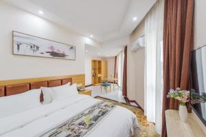 ein Hotelzimmer mit einem Bett und einem Fernseher in der Unterkunft Guilin Wanjing Hotel in Guilin