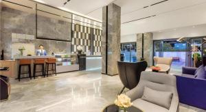 a lobby with a bar and a person in the background at Echarm Hotel Guiyang North High-speed Railway Station in Guiyang