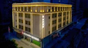 a large white building with lights on it at night at Echarm Hotel Wuhan High-speed Rail Peace Park Metro Station in Wuhan
