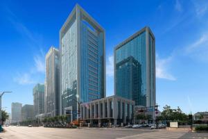 deux grands bâtiments en verre dans une ville avec une rue dans l'établissement Borrman Hotel Ji'nan Aoti Center East Provincial Hospital, à Jinan