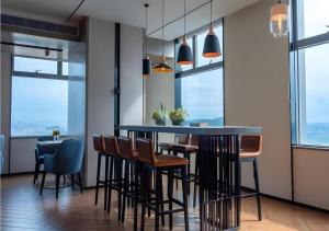 a dining room with a bar with chairs and windows at Echarm Hotel Nanning Wuxiang Headquarters Base in Nanning