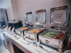 ein Buffet mit drei Tabletts Essen auf der Theke in der Unterkunft Borrman Hotel Changsha Wuyi Square Yingbin Road Metro Station in Changsha