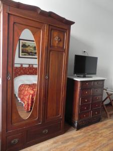 1 dormitorio con un gran armario de madera con espejo en Hotel Beltran en Colonia del Sacramento