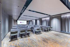 a conference room with tables and chairs and a screen at Echarm Hotel Nanning the MixC Dongmeng Business District in Nanning