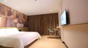 a hotel room with a bed and a flat screen tv at City Comfort Inn Huizhou Zhongkai Huitai Industrial Park in Huizhou