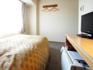 a bedroom with a bed and a flat screen tv at Hotel Trend Nagano in Nagano