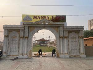 BhauliHotel O Mansa Lawn & Banquets的拱门内有两个人和一条狗 更多4张照片