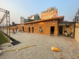 BhauliHotel O Mansa Lawn & Banquets的一栋正在施工的建筑物外站着人。