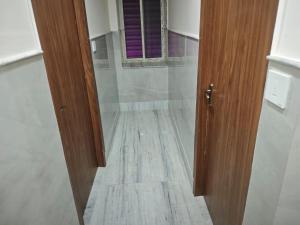 a bathroom with a wooden door and a tile floor at Hotel O Netaji Metro Station Kolkata Formerly Mahamaya Step Inn in Thakurpukur