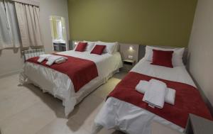 a bedroom with two beds with red and white sheets at Estepa Hotel in General Roca