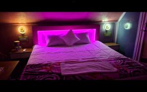 Un dormitorio con una cama morada y luz morada. en Youon, en Bakkhali 5 fotos más