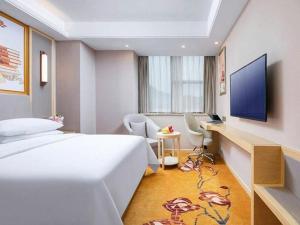 ChengxiにあるVienna Hotel Shanghai Songjiang Xiaokunshanのベッドと机とテレビがあるホテルの部屋