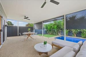 a living room with a couch and a table and a pool at Beachfront Mid Coast Escape in Seaford