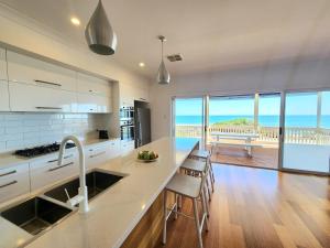a kitchen with a sink and a counter with chairs at Beachfront Mid Coast Escape in Seaford +14 photos