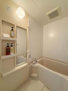 ein Badezimmer mit Badewanne und Spiegel in der Unterkunft Grandeur by b hotel - Cozy Studio in Perfect Spot Walk to Peace Park in Kami-nagarekawachō