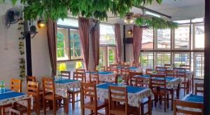 a dining room with blue tables and chairs and windows at THOUSAND-TEN THOUSAND HOTEL in Sathani Wat Sing