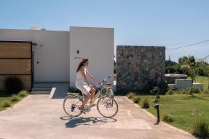 a woman in a white dress riding a bike at Aphrodite Luxury Suites with private heated pools in Kos Town