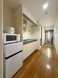 eine Küche mit weißen Geräten und Holzböden in der Unterkunft Grandeur by b hotel - Riverside Studio Near Peace Park in Kami-nagarekawachō